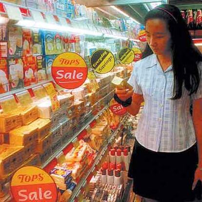 Una mujer mira las estanterías de mantequilla y lácteos en un supermercado de Bangkok.