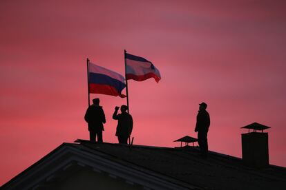Ciudadanos cosacos izan una bandera rusa y una bandera de Crimea en el techo del edificio del Ayuntamiento de Bakhchysarai, ciudad de Crimea, Ucrania.