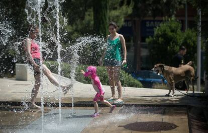 Una familia se refresaca en una fuente de Barcelona.