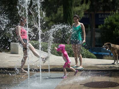 Una familia se refresaca en una fuente de Barcelona.