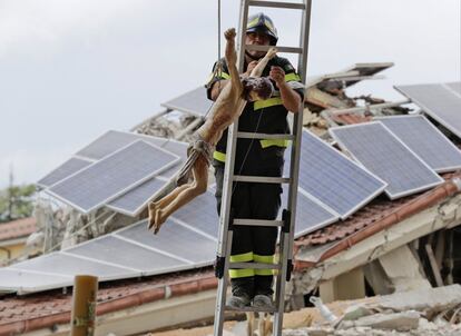 Un bombero cuelga un crucifijo antes del funeral por las víctimas del terremoto, en Amatrice. 