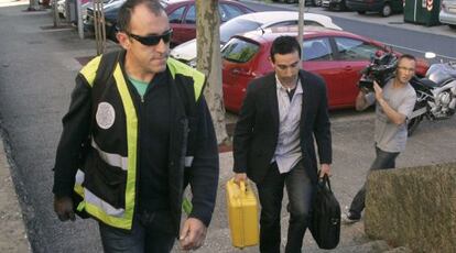 Agentes de la policía llegan al juzgado, ayer, con la caja negra del tren (que en realidad es amarilla).