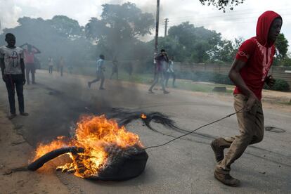 Un manifestante arrastra un neumático en llamas durante los altercados que se han producido en Harare.