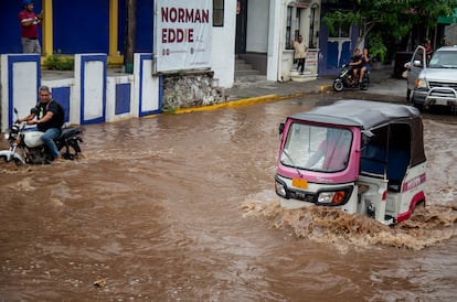 Vehículos transitan por una calle inundada tras el paso de Erick, este jueves, en Juchitán, Oaxaca.