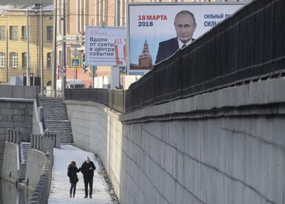 Una pareja camina frente a un cartel de campaña del presidente Vladimir Putin, el 15 de enero de 2018 en San Petersburgo. 