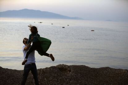 A Syrian migrant holds up her daughter as lifejackets float on the water after their arrival from Turkish coasts at a beach in Mytilene, on the northeastern Greek island of Lesvos, early Tuesday, June 16, 2015. Lesvos has been bearing the brunt of a huge influx of migrants from the Middle East, Asia and Africa crossing from the Turkish coast to nearby Greek islands. More than 50,000 migrants have arrived in Greece already this year, compared to 6,500 in the first five months of last year. (AP Photo/Thanassis Stavrakis)