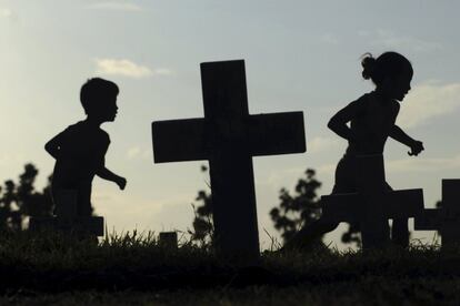 Unos niños corren entre las cruces del cementerio Libingan Ng Mga Bayani, en Taguig, Manila (Filipinas).