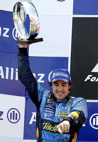 Fernando Alonso levanta su trofeo en el podio.