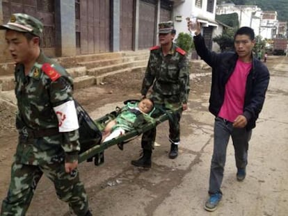 Uma equipe de resgate transporta uma criança ferida no terremoto.