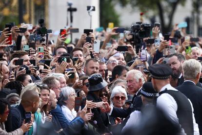 Carlos III de Inglaterra saluda a los ciudadanos que se agolpan a las puertas del palacio de Buckingham.