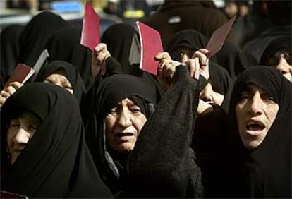 Mujeres iraníes muestran sus identificaciones para votar, ayer ante un colegio electoral de Teherán.