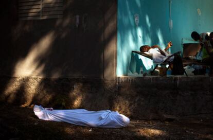 El cadáver de una mujer yace en un centro de tratamiento del cólera en Limbe, cerca de Cabo Haitiano, al tiempo que un enfermo recibe tratamiento contra la bacteria.