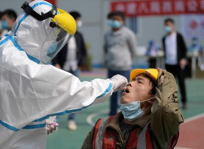 Personal sanitario efectúa la prueba del coronavirus a un trabajador en Wuhan