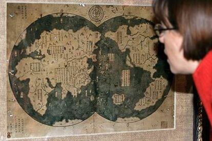 Una mujer examina atentamente el mapa que muestra las costas de medio mundo, y que supuestamente alcanzó en el siglo XV el navegante chino Zheng He. Entre ellas, la de América, a la que habría arribado siete décadas antes que Colón.
