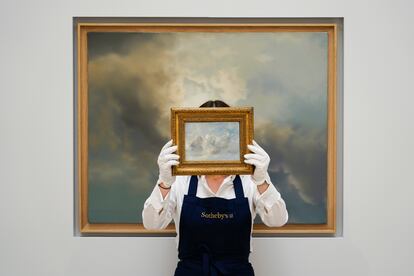 Un miembro del personal sostenía este miércoles la pintura 'Cloud Study' de John Constable, con el telón de fondo de 'Study for Clouds' de Gerhard Richter, en la casa de subastas londinense de Sotheby's.