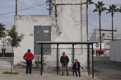 Vecinos en una parada de autobús de El Palmar de Troya.