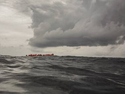 Migrantes a bordo de un bote que partió de Libia aguardan su rescate en el Mediterráneo Central.