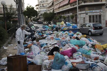 Un trabajador rocía con un producto una pila de basura en el barrio de Piraeus, cerca de Atenas. Los basureros llevan dos semanas de protesta, dejando montones de desperdicios alrededor de la capital griega, bajo las altas temperaturas veraniegas.