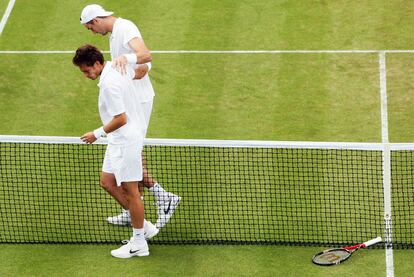 John Isner, con  gorra, y Nicolas Mahut abandonan la pista tras el partido.