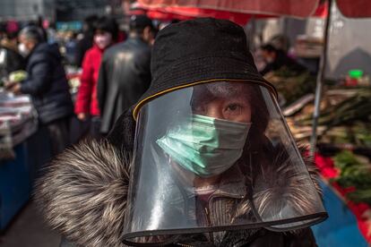 Una mujer camina entre los puestos de un mercado de Pekín (China), el 28 de febrero.