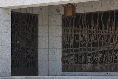 En la fachada anterior, un porche con artesonado en madera muestra dos puertas enrejadas en bronce marrón con motivos sacros, como mitras, báculos y cálices, más otros prosaicos, como un cuchillo de carnicero.