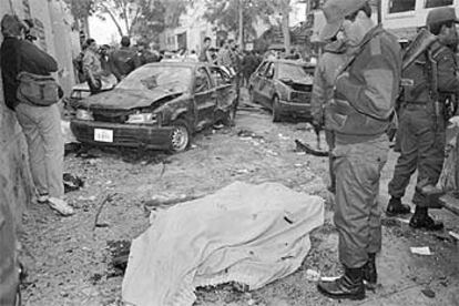 Un policía observa un cadáver tras un atentado de Sendero Luminoso en Lima en 1995.