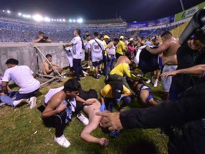 Varios aficionados tratan de ayudar a personas heridas tras la estampida en el Estadio Cuscatlán de El Salvador, donde han muerto al menos 12 personas.