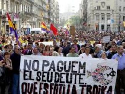 Varias personas sostienen una pancarta durante la manifestación contra la "troika" que esta tarde ha recorrido las calles de Barcelona.