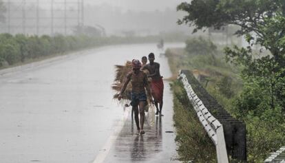 Dos agricultores se trasladan a lugares más seguros durante los vientos racheados previos a la llegada del ciclón, este viernes.