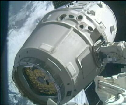 La nave Dragón sujeta por el brazo articulado de la Estación Espacial Internacional.