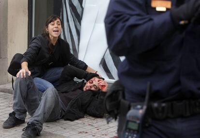 Una mujer ayuda a un manifestante herido en los enfrentamientos con la policía durante la huelga general del 14-N en Valencia