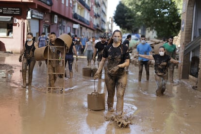 Una multitud de voluntarios arrastran sus cubos por una calle de Massanassa, este sábado. 