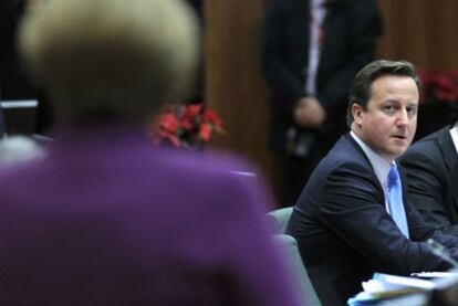 El primer ministro británico, David Cameron, observa a la canciller Angela Merkel (de espaldas) durante la cumbre europea.