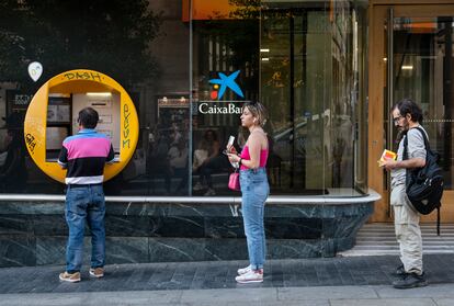 Varias personas hacen cola para sacar dinero frente a un cajero, en junio en Madrid.