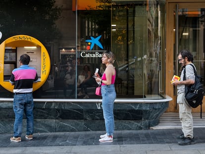 Varias personas hacen cola para sacar dinero frente a un cajero, en junio en Madrid.