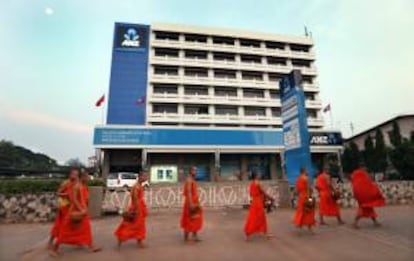 Monjes budistas caminan frente a los cuarteles del banco australiano ANZ, un día antes de la novena Cumbre Asia Europa (ASEM) en Vientiane, Laos.