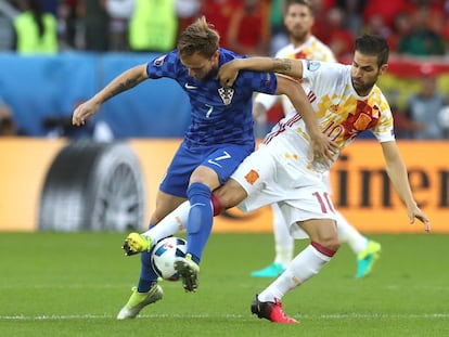 Ivan Rakitic (i) y Cesc Frabregas luchan por la pelota.