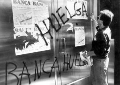 Un miembro de un piquete realiza una pintada en una sucursal durante una huelga de banca.