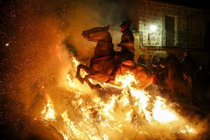 Un jinete montado en su caballo pasa sobre una hoguera durante la celebración de las 'luminarias', en San Bartolomé de Pinares (Ávila).