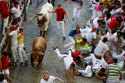 Varios corredores caen al paso de los toros de la ganadería Álvaro Núñez, durante el tercer encierro.