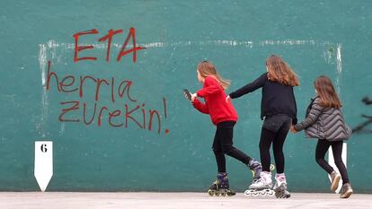 Tres niñas juegan junto a un frontón con pintadas a favor de ETA.