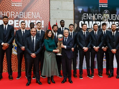 La presidenta de la Comunidad de Madrid, Isabel Díaz Ayuso, sostiene el trofeo de Copa junto al presidente Florentino Pérez, y todo el equipo.