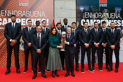 La presidenta de la Comunidad de Madrid, Isabel Díaz Ayuso, sostiene el trofeo de Copa junto al presidente Florentino Pérez, y todo el equipo.