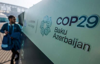 Un hombre pasa junto a uno de los carteles de la COP29, que debería cerrarse este viernes en Bakú (Azerbaiyán).