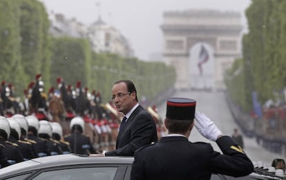 Hollande se acerca al Arco de Triunfo durante un paseo en coche bajo una intensa lluvia que ha empapado su traje pero por el que ha recibido el calor de sus seguidores en las calles.