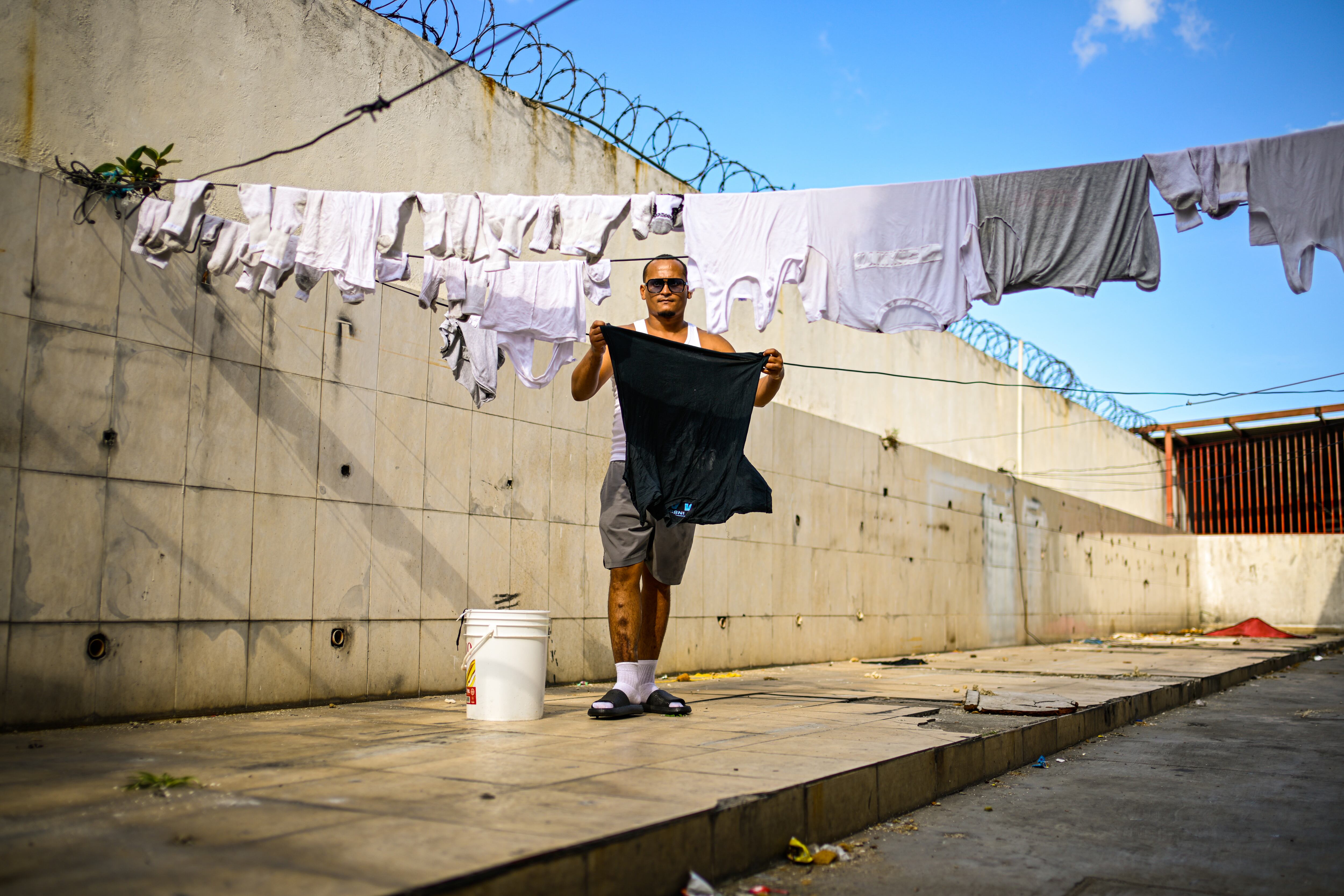 Yeiker García, tiende su ropa para secarla en el patio del refugio La Posada de Catia.