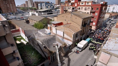 Los vecinos protestan al pie de la calle, mientras la excavadora derriba la vivienda en El Cabanyal. Al fondo, la avenida Blasco Ibañez que la alcaldesa pretende prolongar destruyendo las viviendas.
