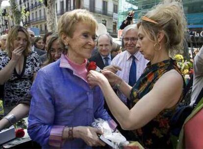 Una florista coloca una rosa a Maria Teresa Fernández de la Vega, que ayer paseó por las Ramblas.