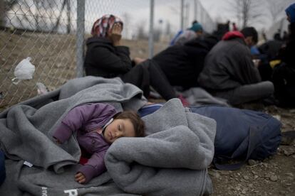 Un ni?o duerme mientras un grupo de refugiados resperan que se les permitan cruzar la frontera entre Grecia y Macedonia, cerca del pueblo de Idomeni (Grecia).