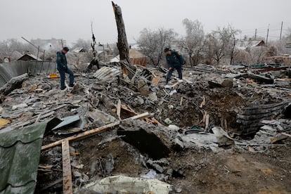 Two officials inspect the ruins of a house destroyed by bombing in the Ukrainian town of Yasynuvata.